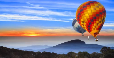 Majestic Hot Air Balloons Drifting Over Golden Sunset Mountain Range image