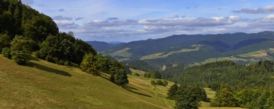 Panoramic Mountain Landscape with Lush Green Forests and Cloudy Blue Sky image