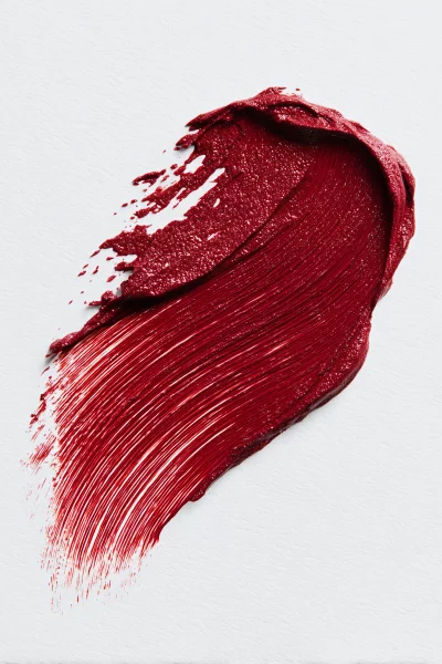 Vibrant Red Cosmetic Swatch with Glitter on Textured White Background