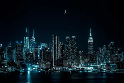 Stunning Night Cityscape with Illuminated Skyscrapers and Crescent Moon Reflected on Water image