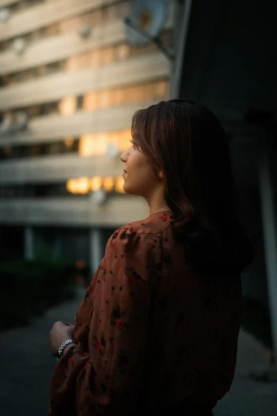 Woman in patterned dress looks into the distance at sunset