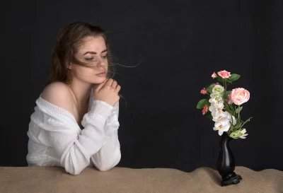 Pensive Young Woman in White Blouse with Clasped Hands and Windswept Hair image