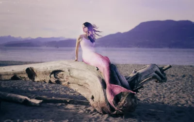 Mystical mermaid sits on weathered driftwood at a peaceful beach, contemplating the ocean view. image