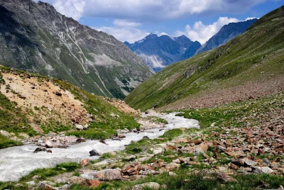 Vibrant Alpine Valley with Rushing Mountain Stream and Green Rocky Slopes image