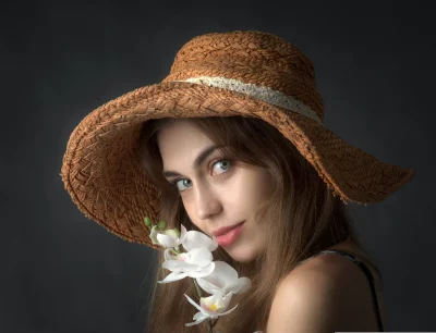 Young Woman in Straw Hat Gazing with Blue Eyes and White Orchid image