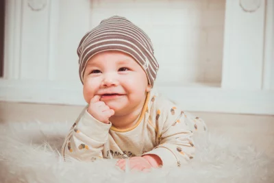 Adorable Baby Smiling Sweetly While Lying on Soft Furry Rug Wearing Striped Hat Cute Infant Joy image