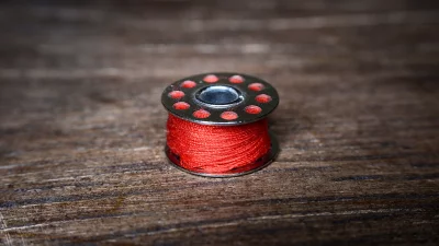 Vibrant Red Thread Bobbin on Rustic Wooden Table image