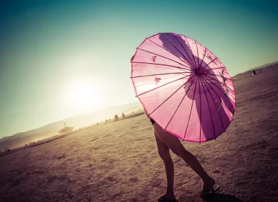 Woman Walking with Pink Umbrella in Cinematic Desert Landscape at Golden Sunset image