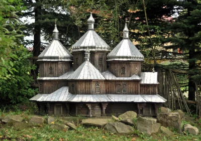 Intricate Miniature Wooden Church Model with Silver Domes Amidst Lush Green Foliage image
