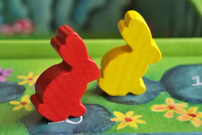 Vibrant Red and Yellow Wooden Rabbit Tokens on a Colorful Board Game image