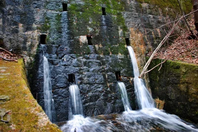 Serene Water Cascading Down Moss-Covered Stone Wall in a Forest Stream image