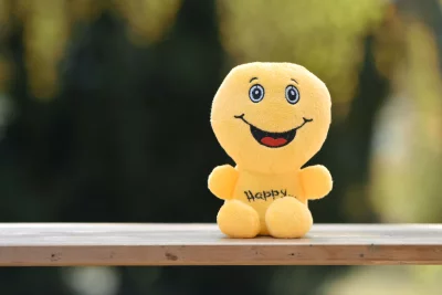 Yellow Smiling Plush Toy on Wooden Surface, Symbolizing Joy and Positivity image