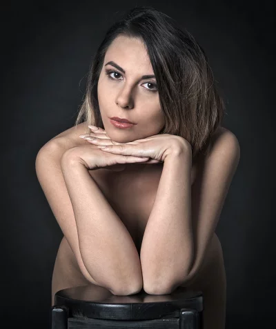 Intense Portrait of Young Woman with Direct Gaze and Bare Shoulders on Dark Background image
