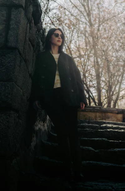 Fashionable Woman Posing Confidently by Stone Wall and Steps in Autumn