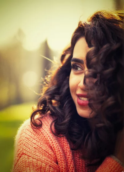 Smiling Woman with Curly Hair in Golden Hour Sunlight