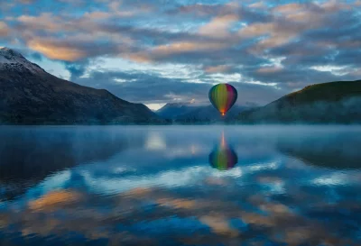 Cinematic Hot Air Balloon Soaring Over Misty Lake at Golden Sunset Wallpaper image