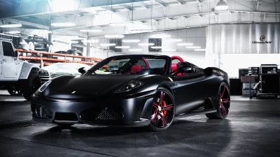 Sleek Matte Black Ferrari F430 Convertible Sports Car with Red Interior in a Professional Garage image