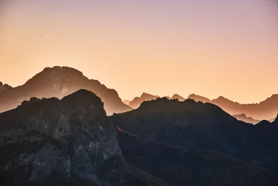 Serene Mountain Silhouettes at Twilight with Gradient Sky and Distant Contrail image
