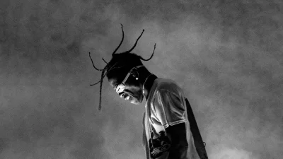 Travis Scott's Energetic Stage Presence in a Dramatic Black and White Concert Photo image