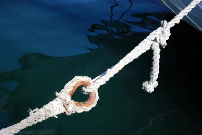 Sturdy Boat Mooring Rope and Rusty Metal Ring in Deep Blue Water image