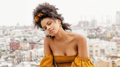 Confident Young Woman in Stylish Off-Shoulder Top Posing on Urban Rooftop image
