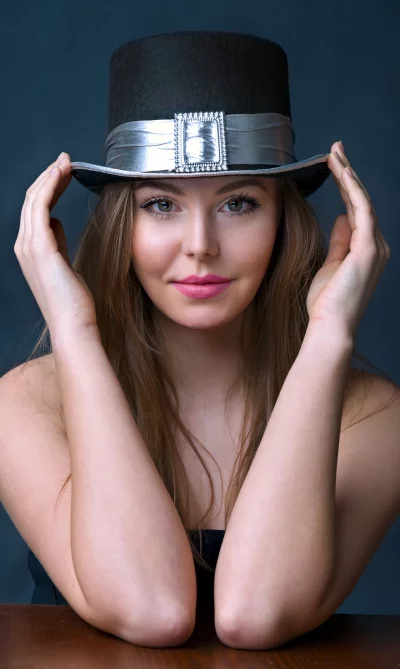 Young Woman Posing Playfully with Black Top Hat and Silver Band image