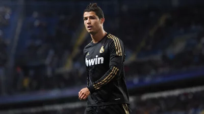 Cristiano Ronaldo in Black Gold Football Kit on Pitch with Focused Gaze image