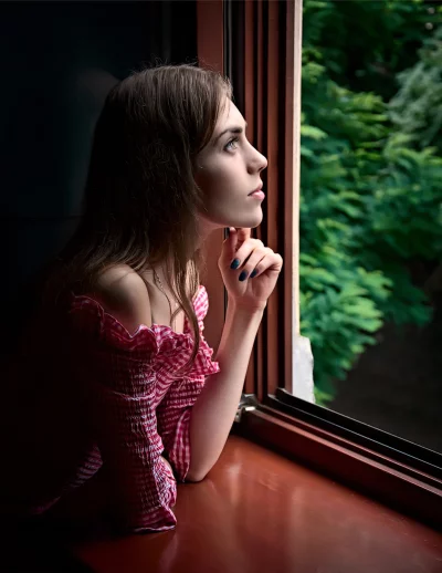 Pensive Young Woman Gazing Out Window with Blue Nails image