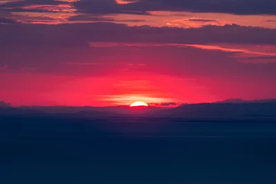 Vibrant Red Sky Sunset over Distant Mountains and Serene Water Landscape image