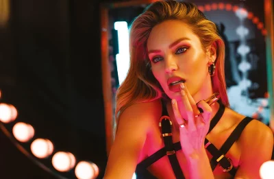 Glamorous Candice Swanepoel Applying Red Lipstick in Neon Lit Studio Portrait image