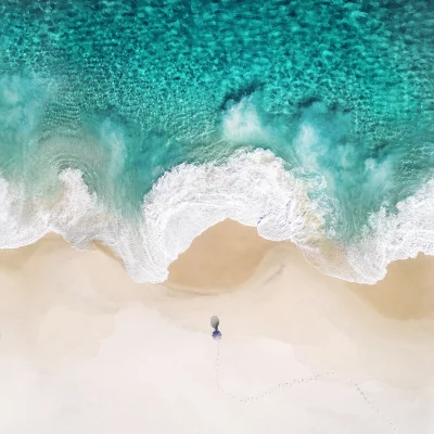 Aerial View of Pristine Tropical Beach, Turquoise Ocean, Crashing Waves, and Lone Walker image