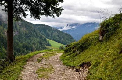 Scenic Alpine Hiking Trail with Green Hills and Cloudy Sky image