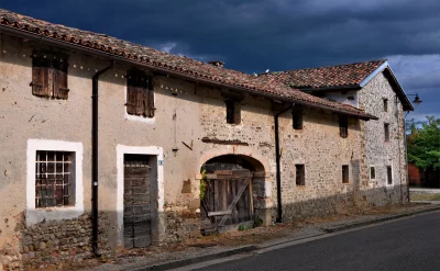 Old Rustic Stone Farmhouse with Terracotta Roof Tiles Under Stormy Sky image