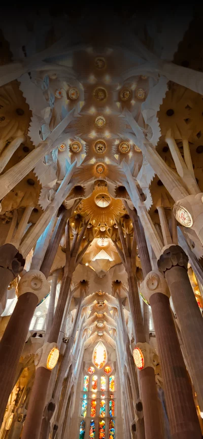 Interior view of the Sagrada Familia showing intricate column and ceiling architecture.
