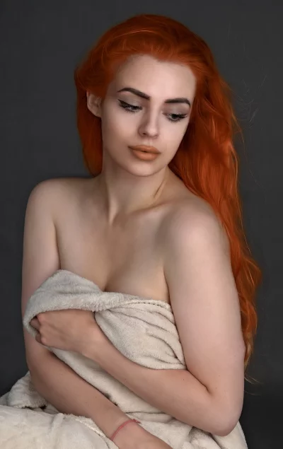 Red-Haired Woman Wrapped in Beige Towel with Bare Shoulders in Pensive Pose image