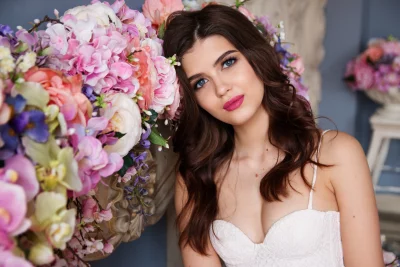 Captivating Young Woman with Blue Eyes Posing with Vibrant Pink and Purple Floral Display image