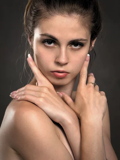 Confident Young Woman with Posed Hands and Intense Gaze Against Dark Background image