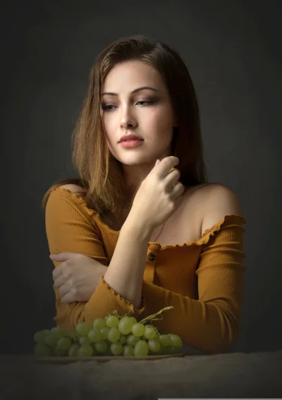 Pensive Young Woman in Mustard Off-Shoulder Top with Fresh Green Grapes image