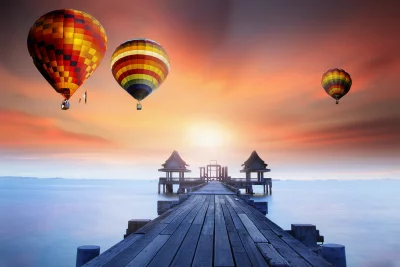 Colorful Hot Air Balloons Soaring Over Serene Ocean Pier at Sunset image