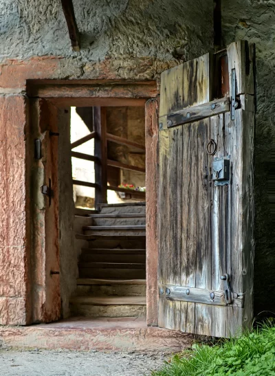 Rustic Stone Building Entrance with Open Wooden Door and Interior Staircase image