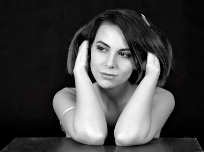 Elegant Black and White Portrait of Young Woman with Reflective Gaze and Hands Near Head image
