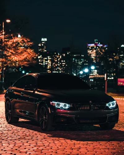 Sleek Black BMW Sports Car with Striking Headlights on Urban Cobblestone Street at Night image