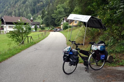 Adventure touring bicycle with sunshade parked on a quiet village road by green mountains image
