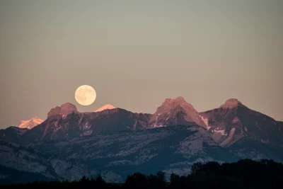 Majestic Full Moon Rising Over Alpine Mountain Range at Dusk image