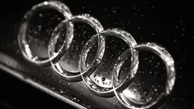 Glistening water droplets on the iconic Audi four-ring emblem in monochrome image