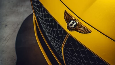 Golden Bentley Emblem on Yellow Luxury Car Grille, Showcasing Automotive Elegance image