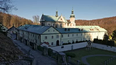 Historic European Monastery Complex with Green Roofs, Bell Tower, and Stone Archway image