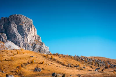 Autumn Dolomites Landscape with Golden Larches, Rustic Huts, and Blue Sky image
