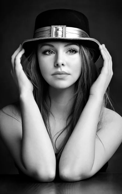 Elegant Young Woman Posing with Stylish Hat in Black and White Portrait image