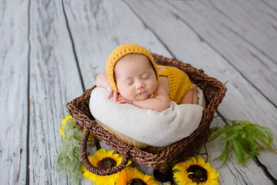 Adorable Newborn Baby Sleeping Peacefully in a Cozy Basket with Bright Sunflowers image